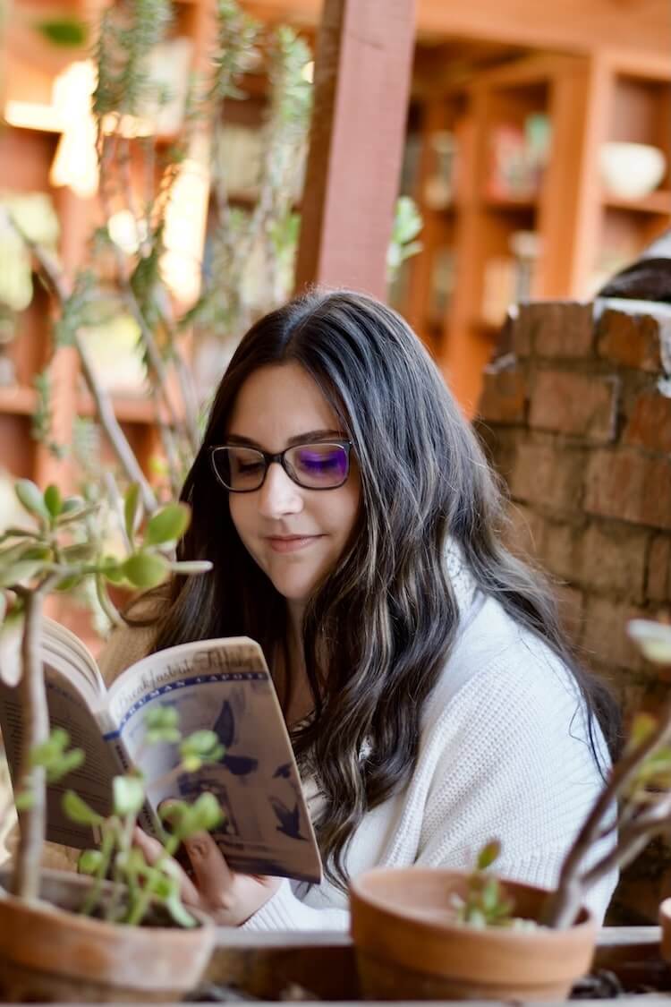 Christina Madden sitting in a chair and reading a book